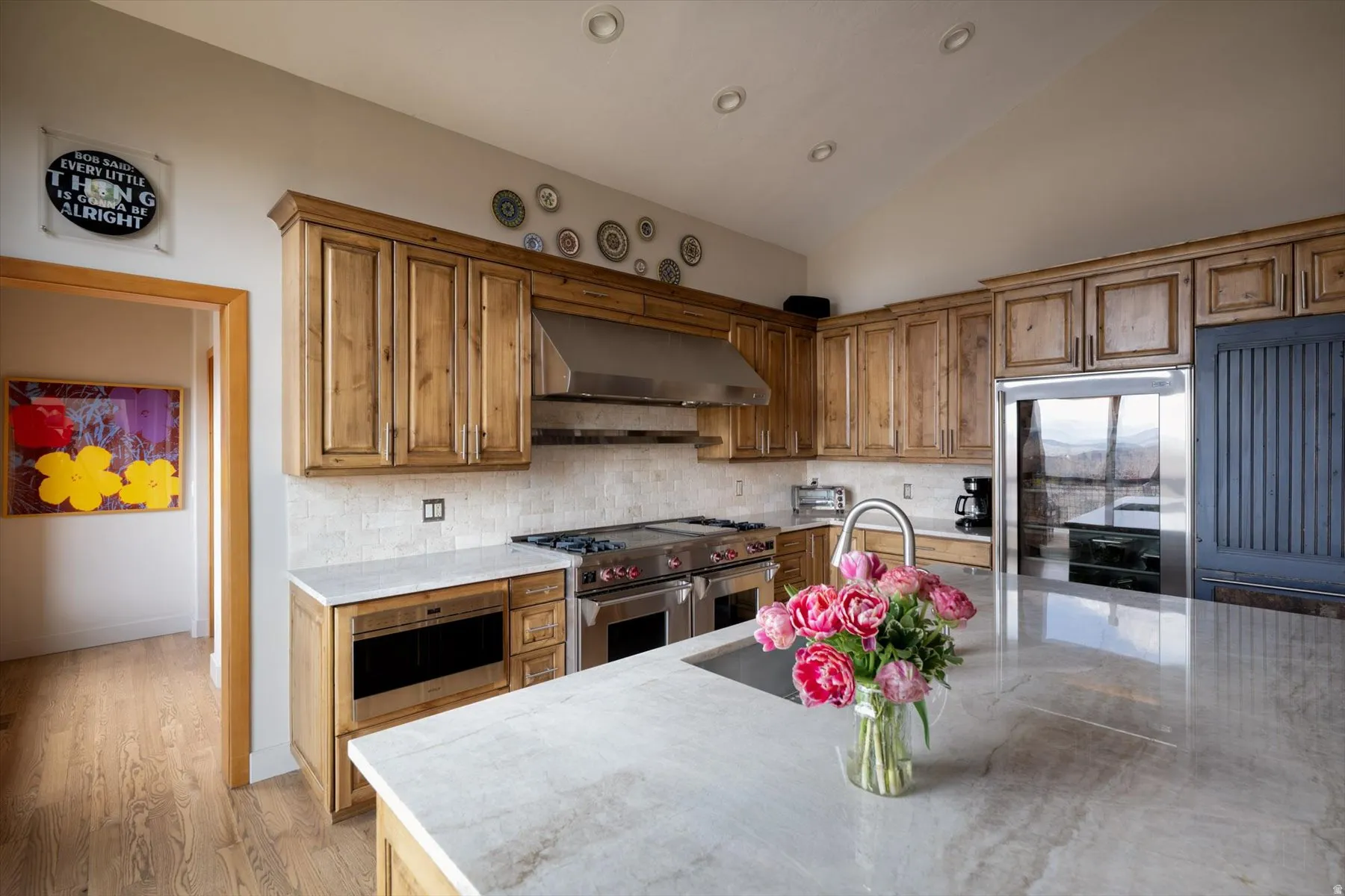 Kitchen with lofted ceiling, stainless steel appliances, backsplash, light wood-style floors, and wood finish cabinets