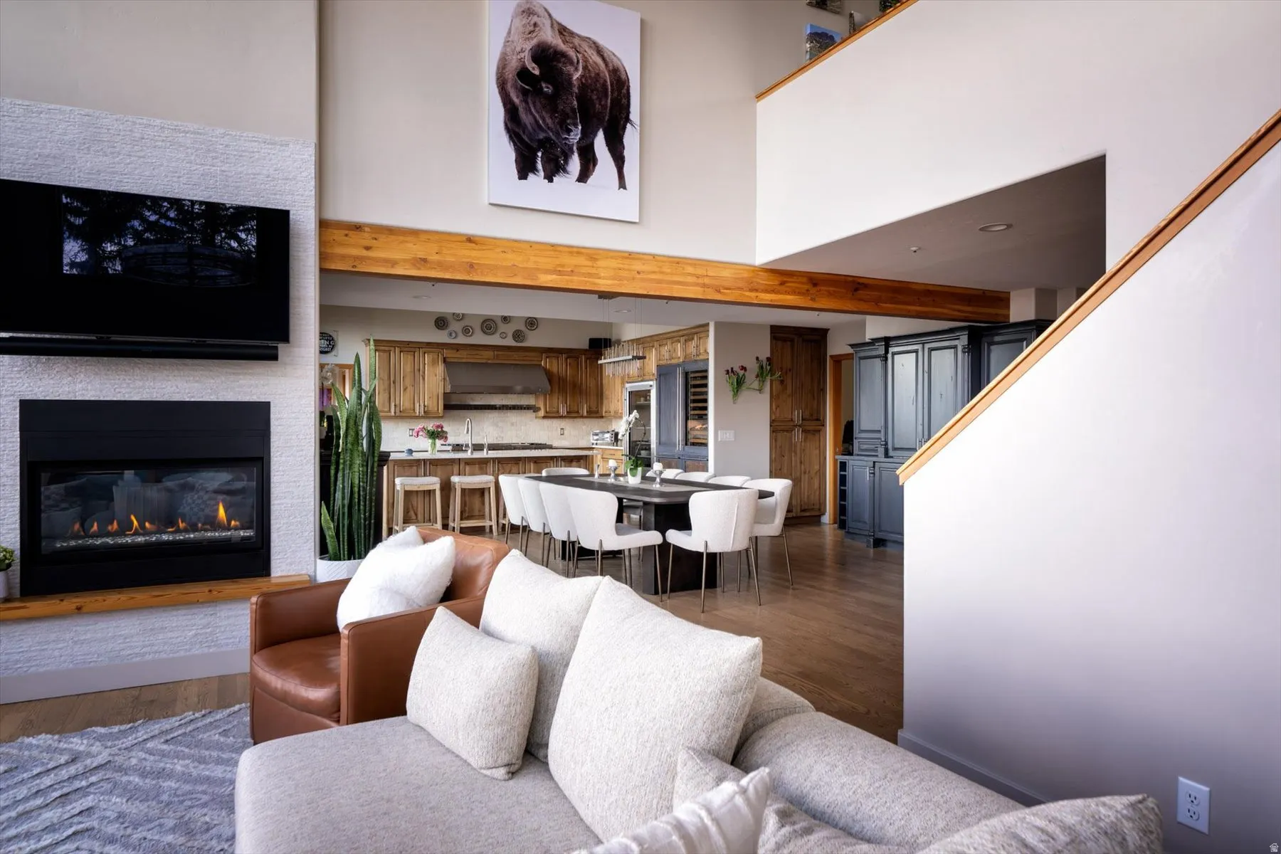 Living area with a glass covered fireplace, wood finished floors, and a high ceiling
