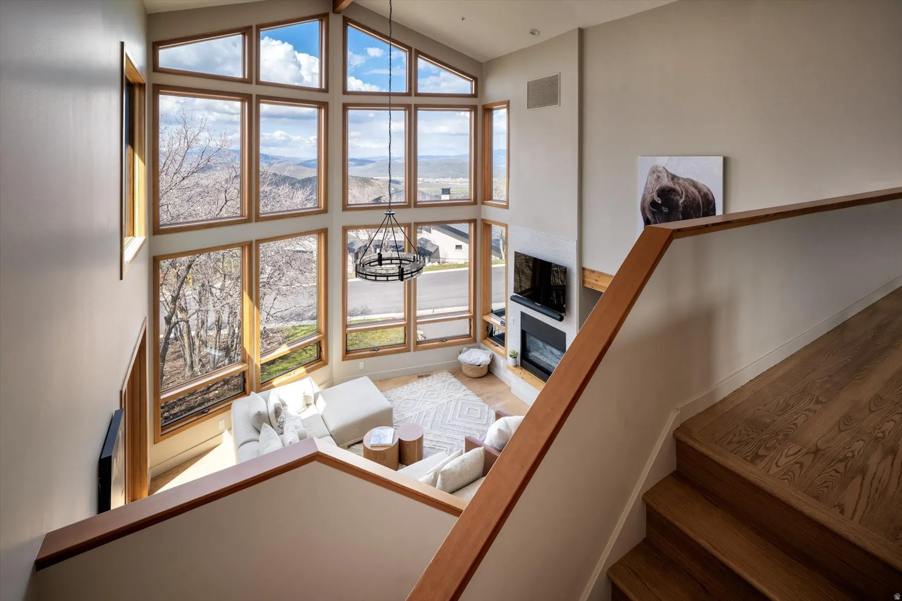 Living room with a glass covered fireplace, vaulted ceiling, and wood finished floors