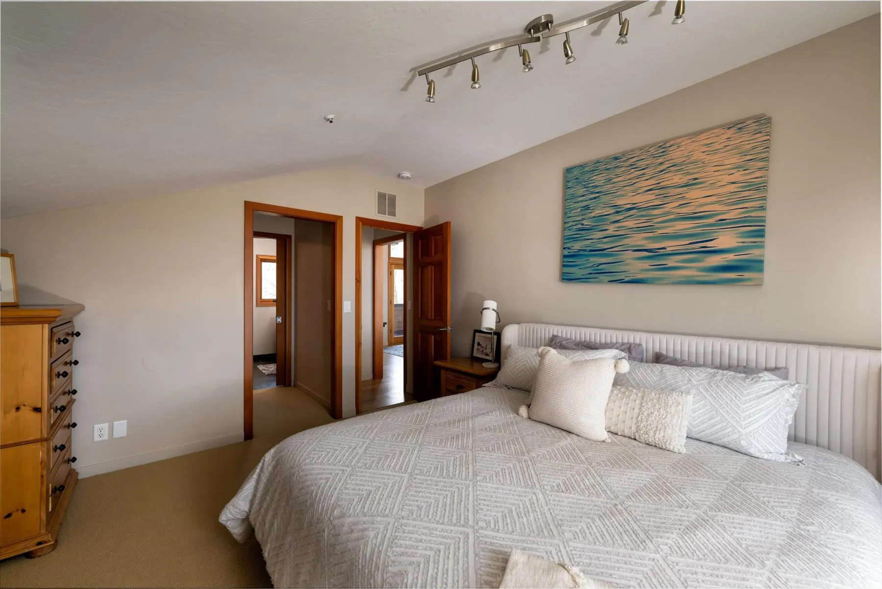 Carpeted bedroom with lofted ceiling and track lighting