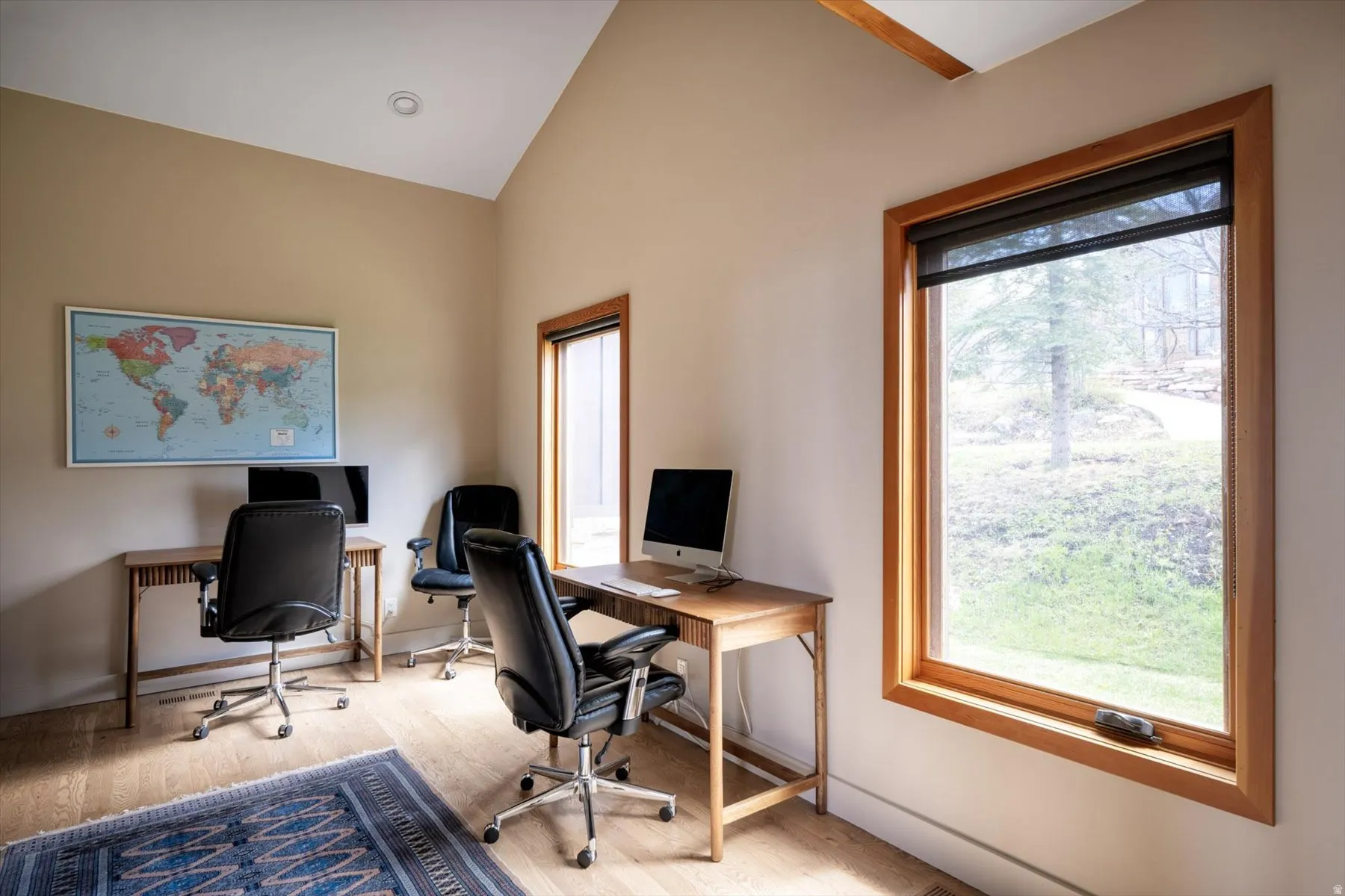 Home office with light wood-style flooring, lofted ceiling, and plenty of natural light
