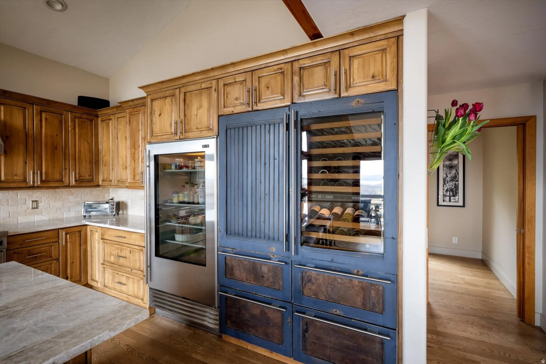 Kitchen featuring vaulted ceiling, wood finish cabinets, dark wood-style flooring, and tasteful backsplash