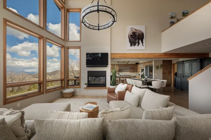 Living room with a glass covered fireplace, a high ceiling, and wood finished floors
