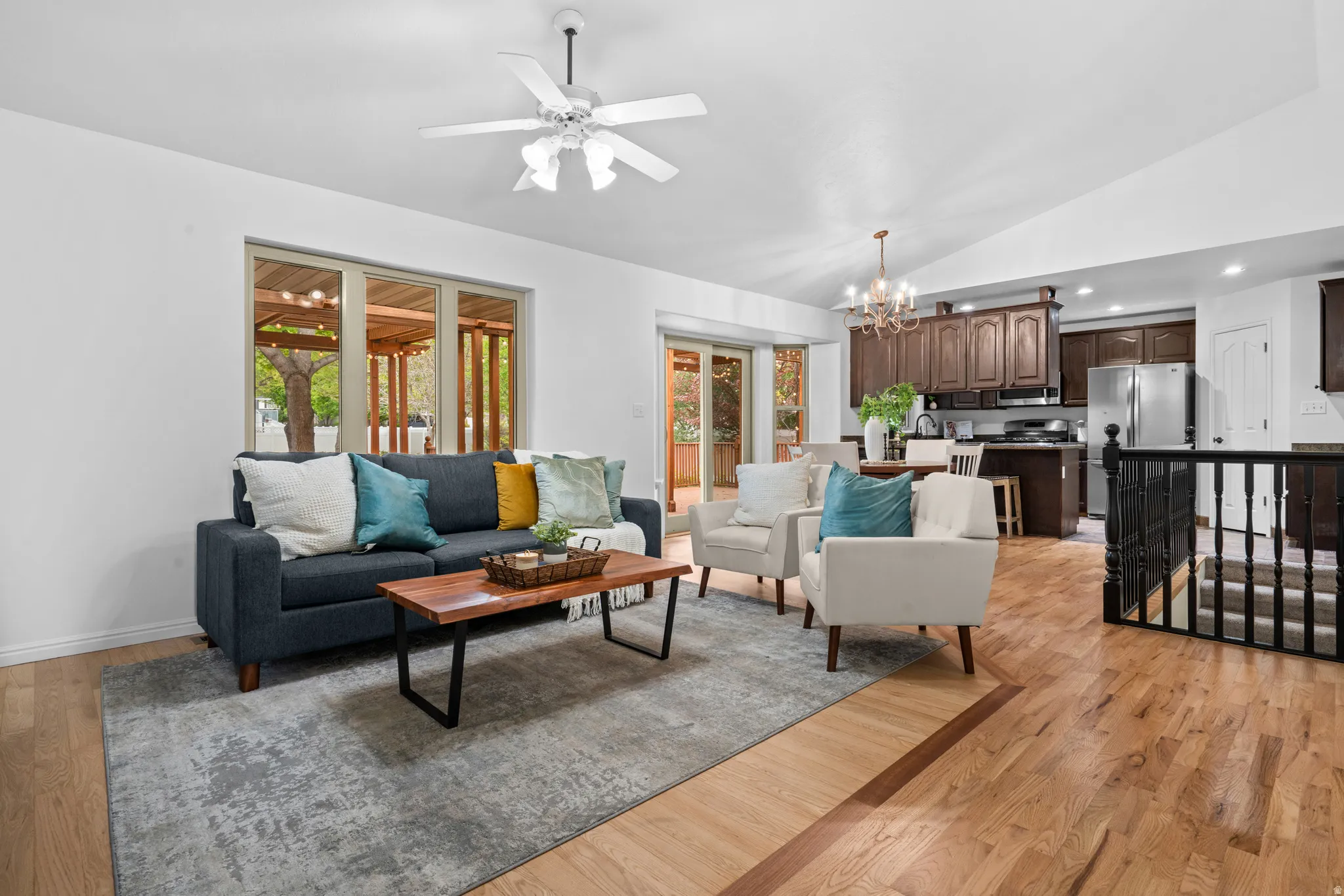 Living area featuring suspended lighting, light wood-style floors, ceiling fan, lofted ceiling, and plenty of natural light
