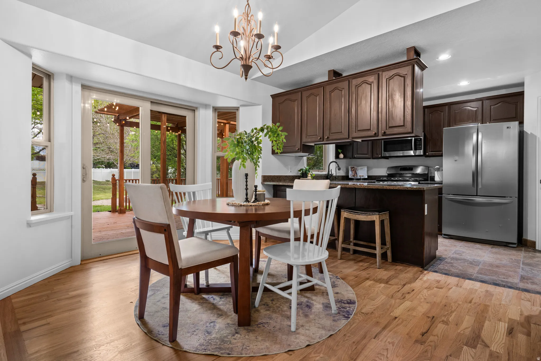 Dining space with suspended lighting, vaulted ceiling, and light wood-style floors