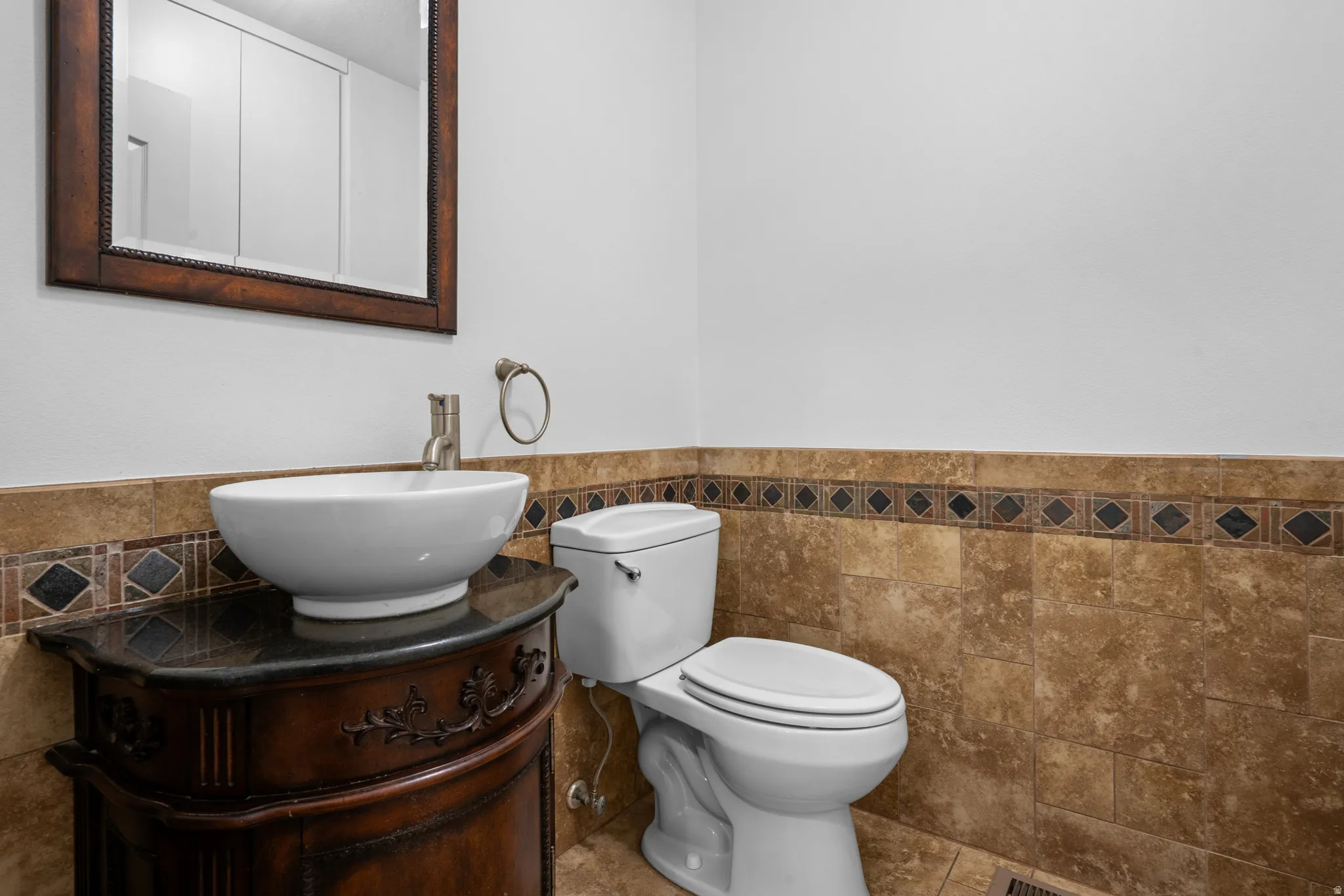 Half bathroom featuring vanity, tile walls, wainscoting, and tile patterned floors