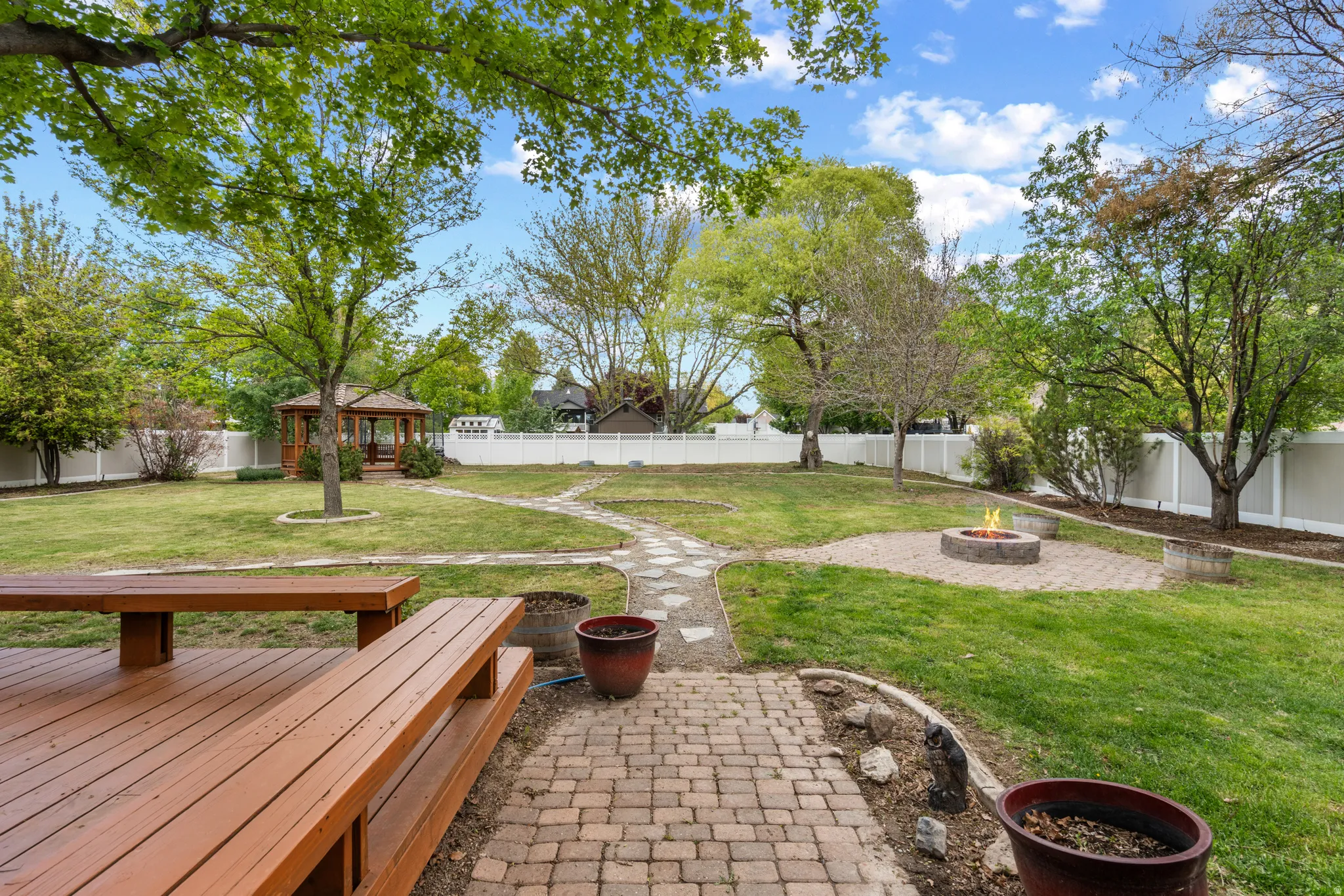Fenced backyard with a fire pit and a gazebo