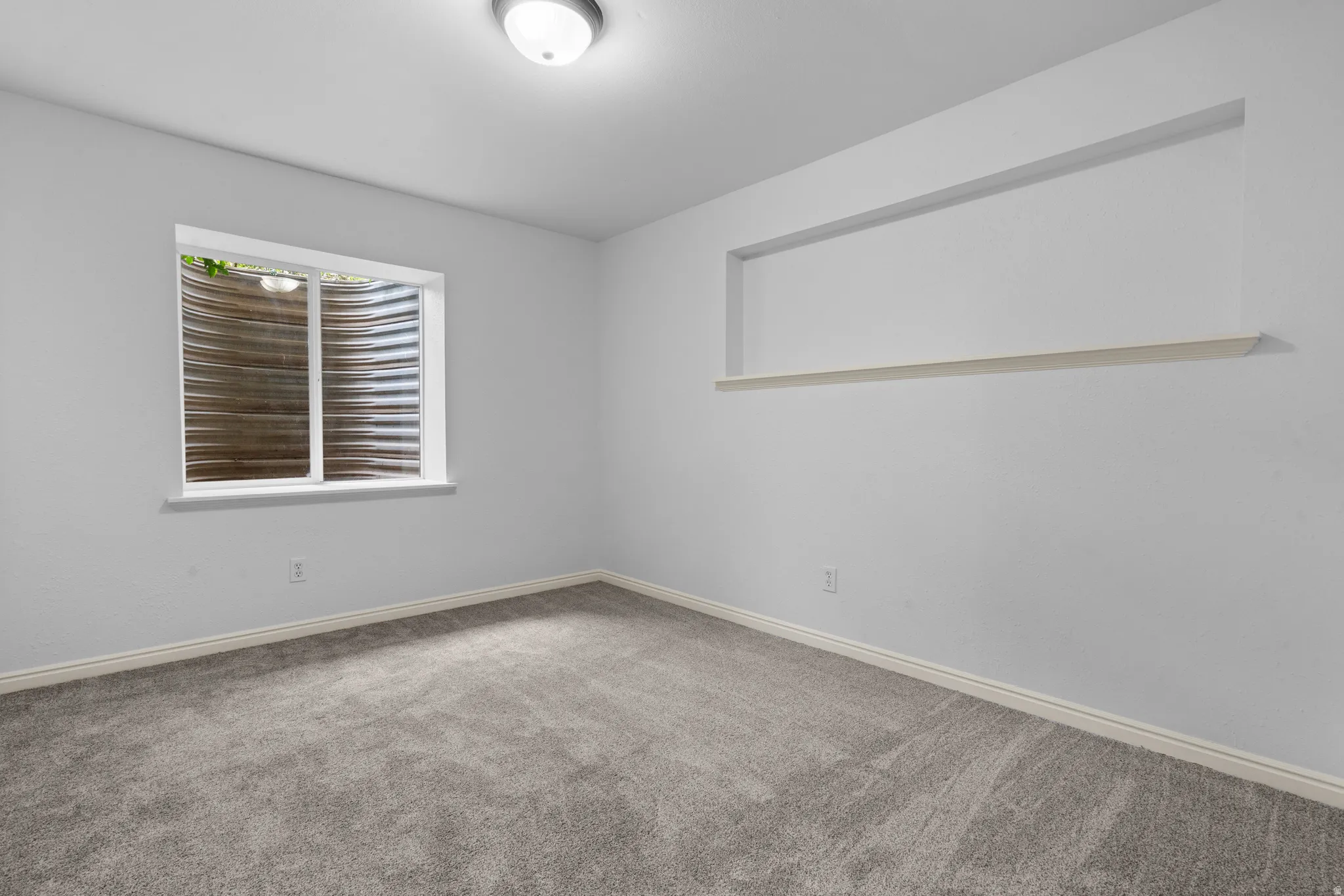 Spare room featuring light colored carpet and baseboards