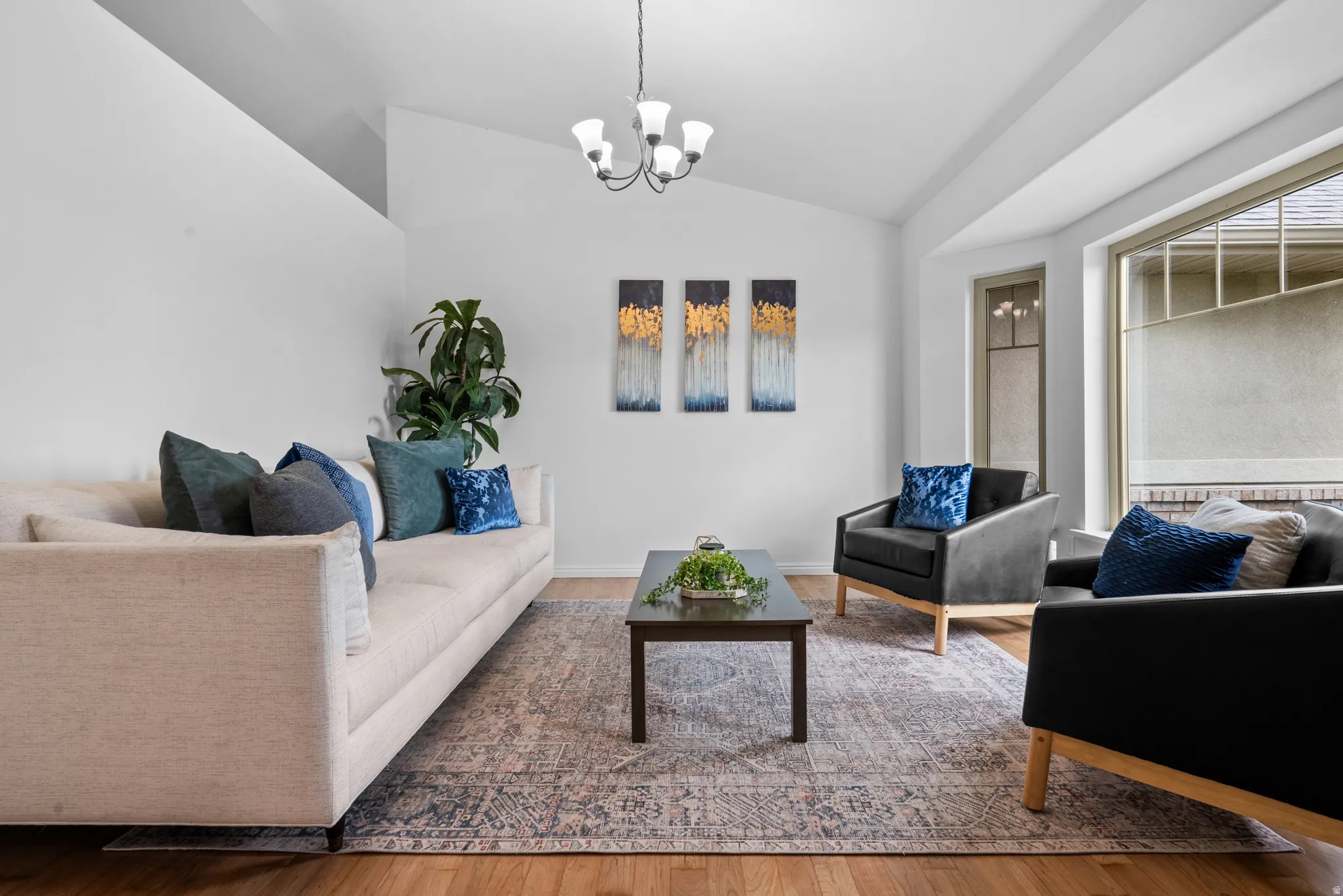 Living area featuring vaulted ceiling, suspended lighting, and wood finished floors