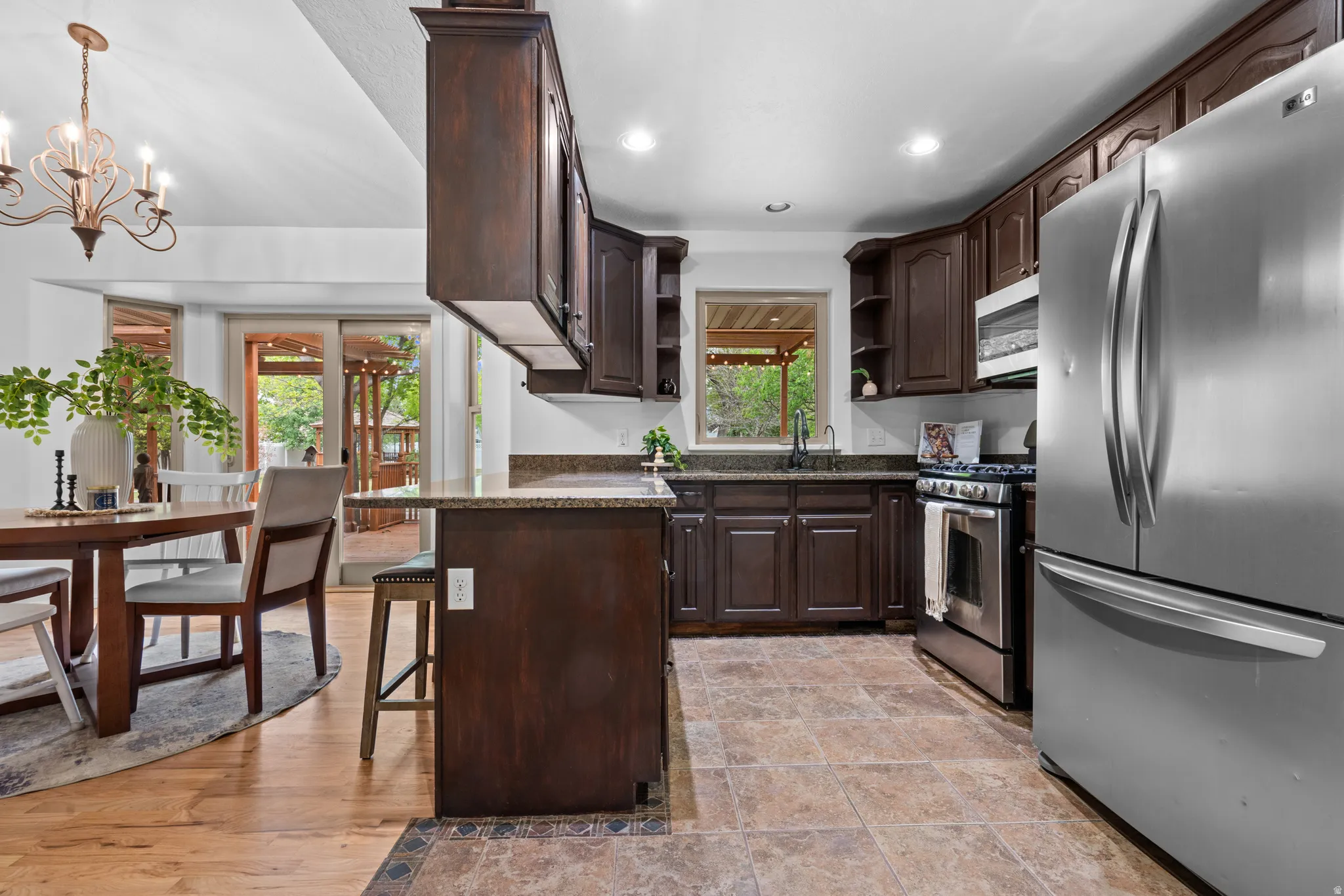 Kitchen with stainless steel appliances, dark stone counters, dark wood finish cabinets, a breakfast bar, and open shelves