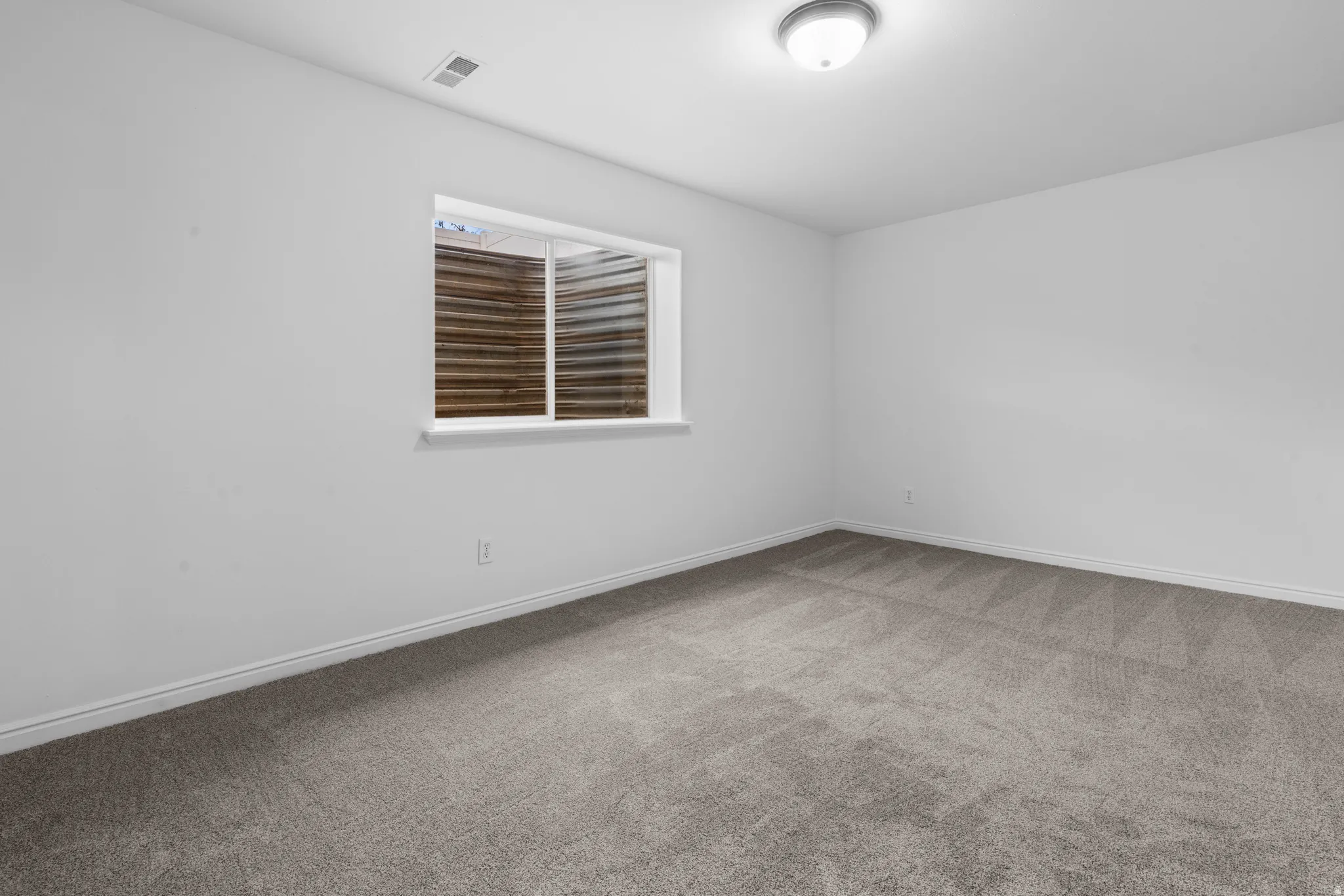Empty room with light carpet and baseboards