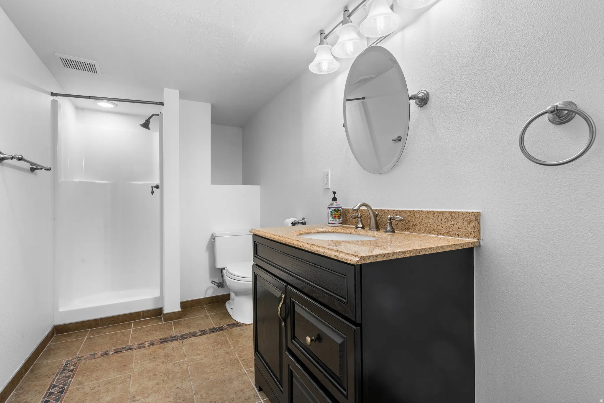 Bathroom with inlaid floor details, vanity, and a shower stall