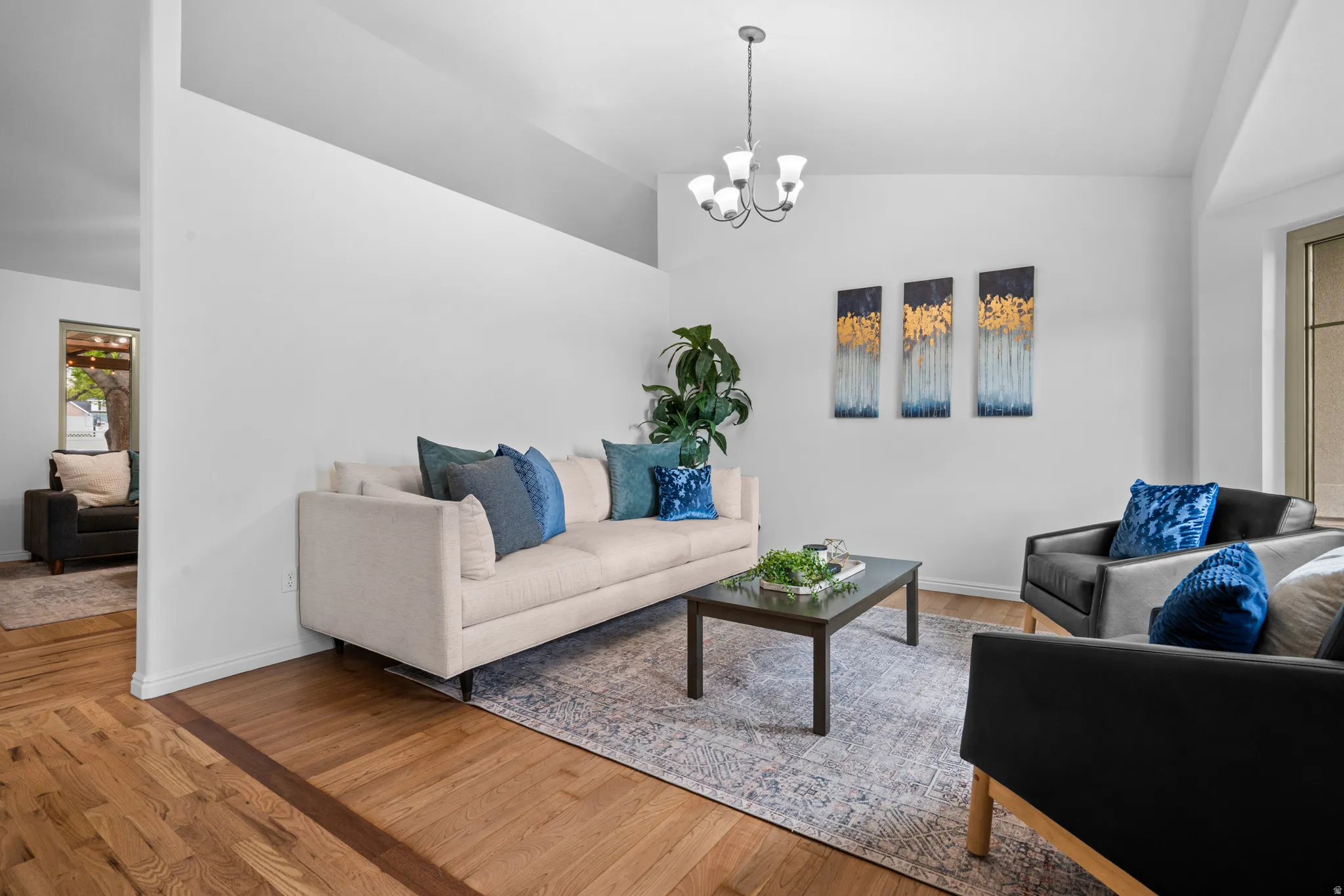 Living area featuring vaulted ceiling, wood finished floors, and hanging lights
