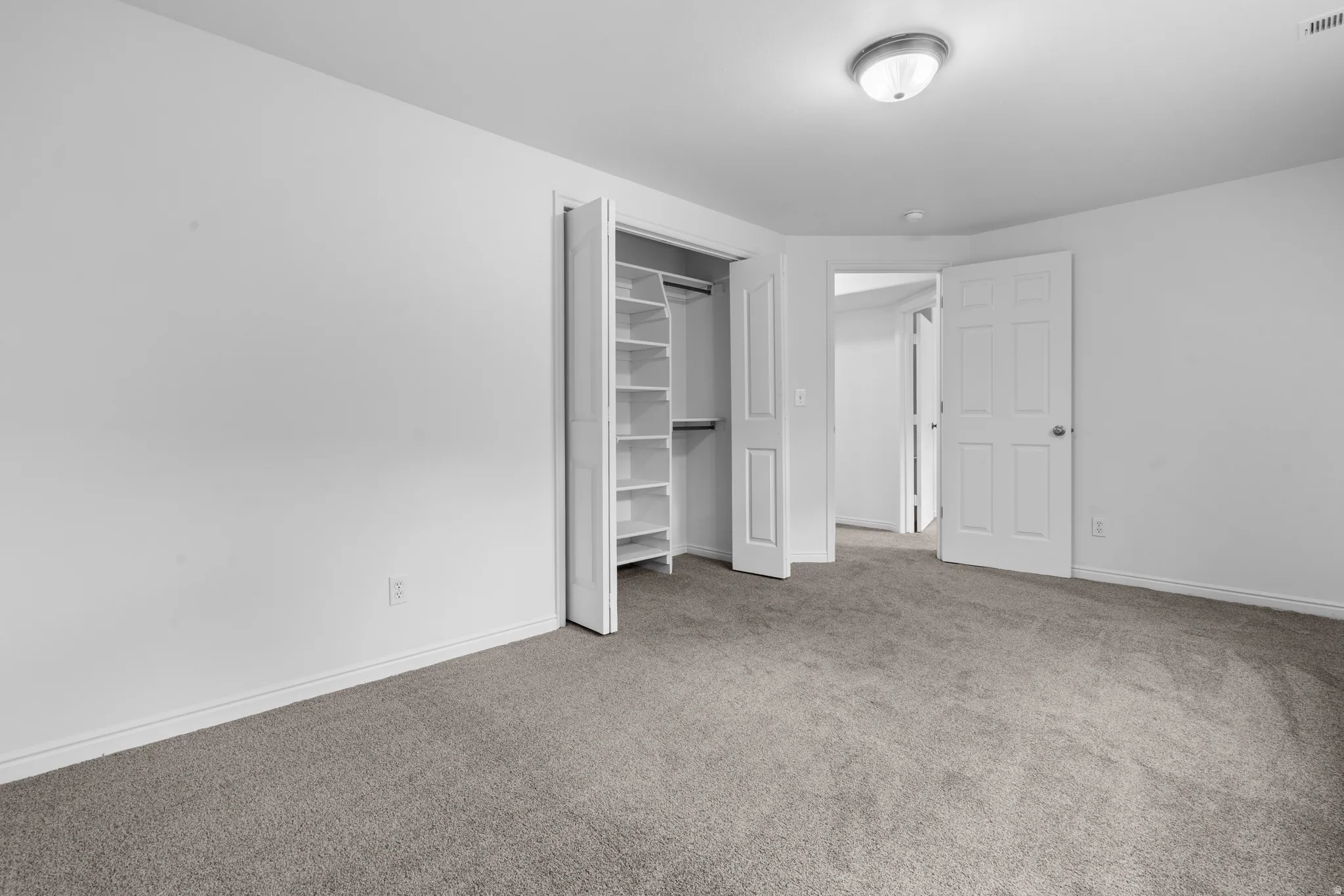 Unfurnished bedroom with light colored carpet and a closet