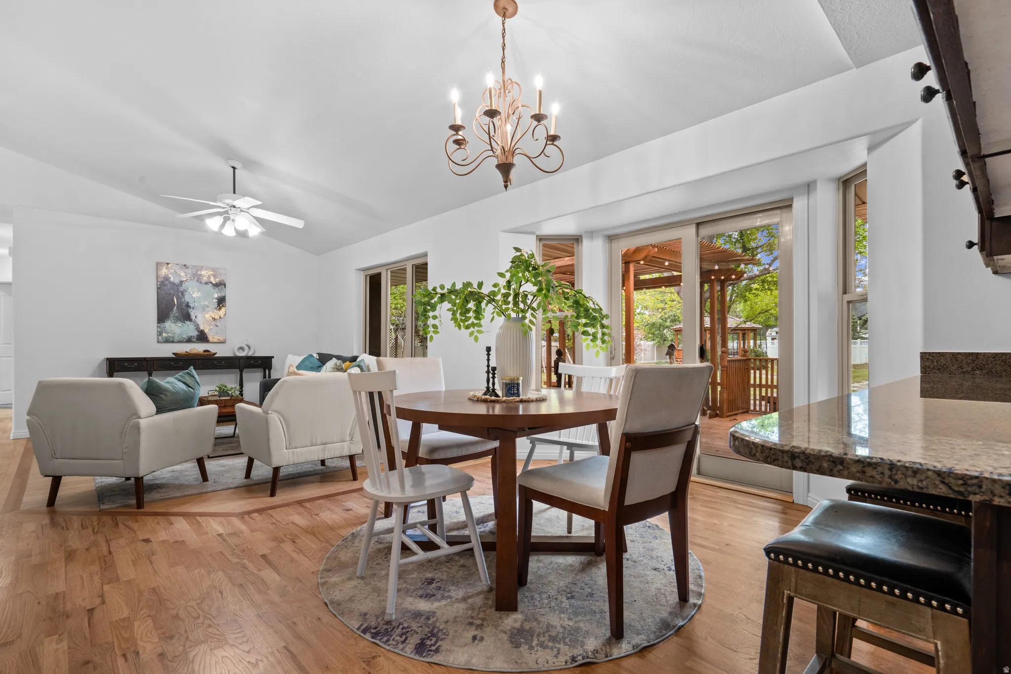 Dining space featuring a ceiling fan, lofted ceiling, light wood-style floors, and suspended lighting
