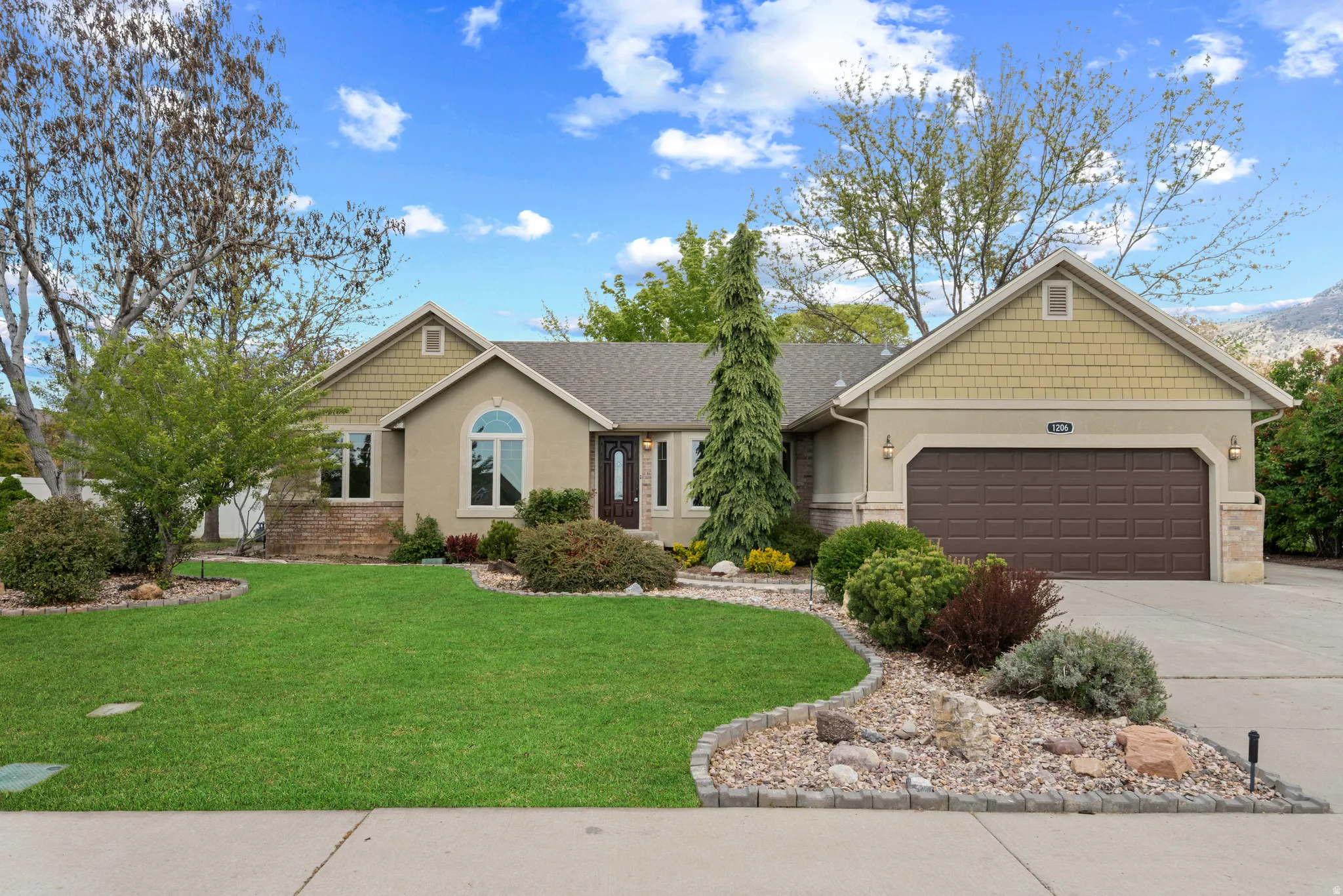 Craftsman house with a front yard, driveway, a garage, and stucco siding
