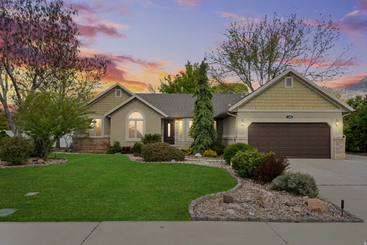 Craftsman-style house with a front lawn, driveway, an attached garage, and stucco siding