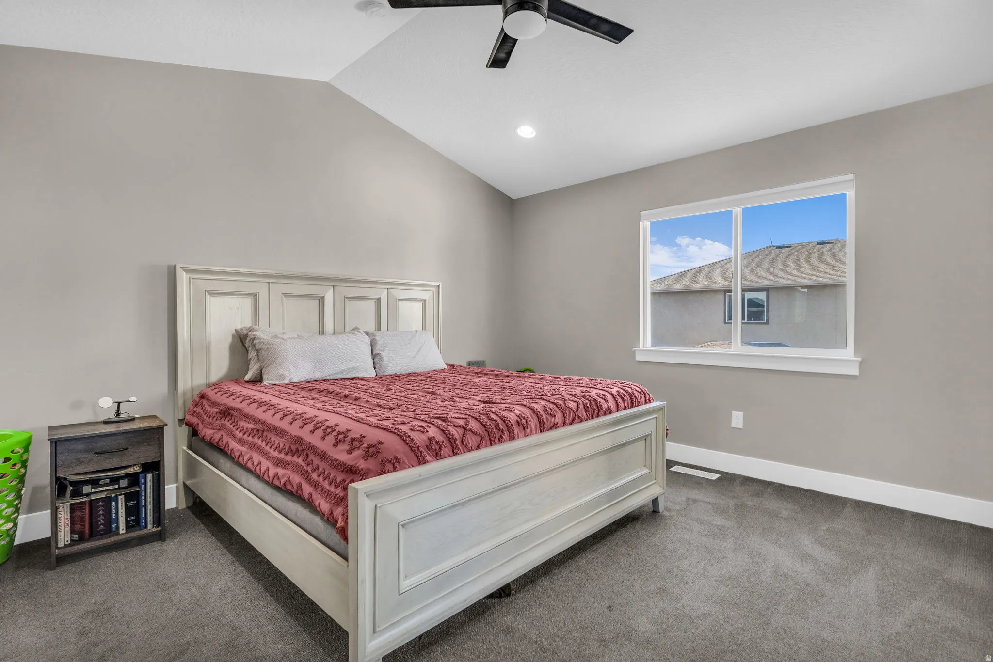 Bedroom with vaulted ceiling, carpet flooring, and a ceiling fan