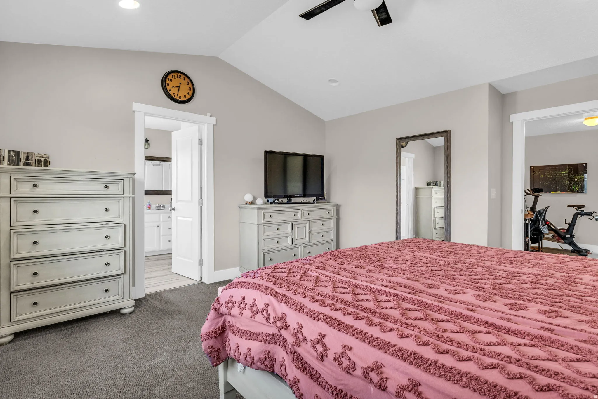Bedroom with ensuite bathroom, dark carpet, and ceiling fan