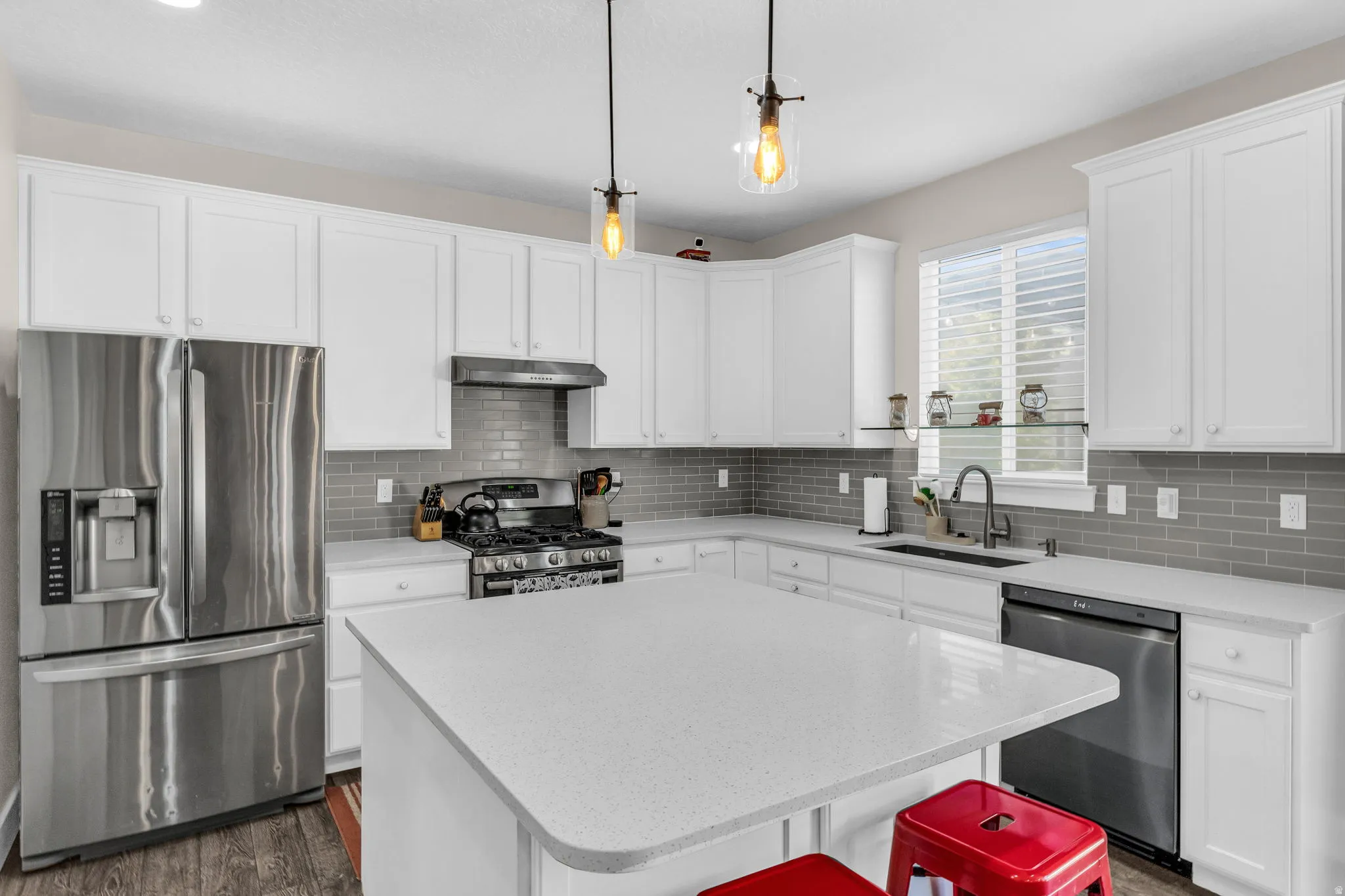 Kitchen with stainless steel appliances, white cabinetry, dark wood finished floors, and a center island