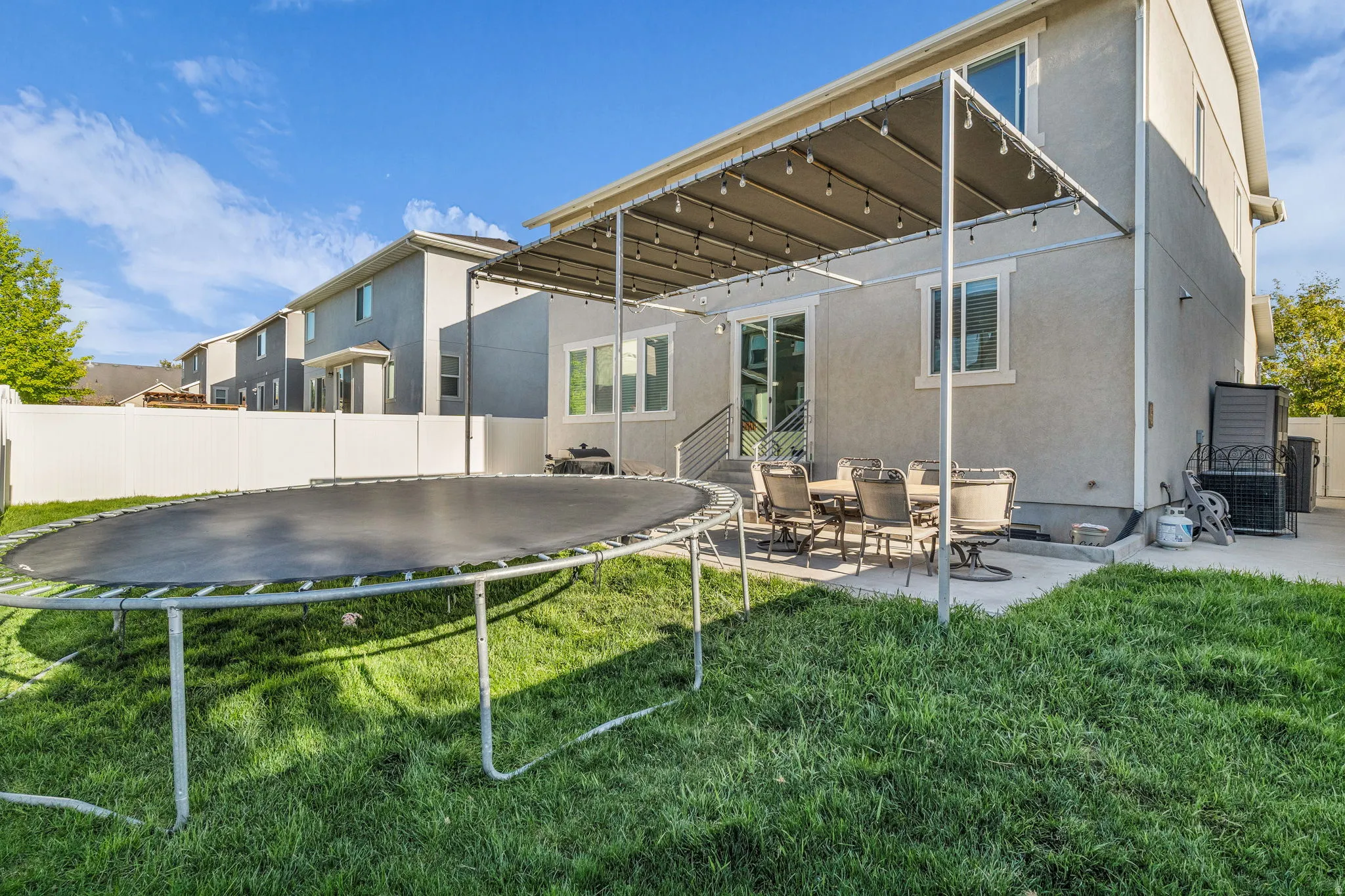 Rear view of property with a patio, a fenced backyard, stucco siding, and a trampoline