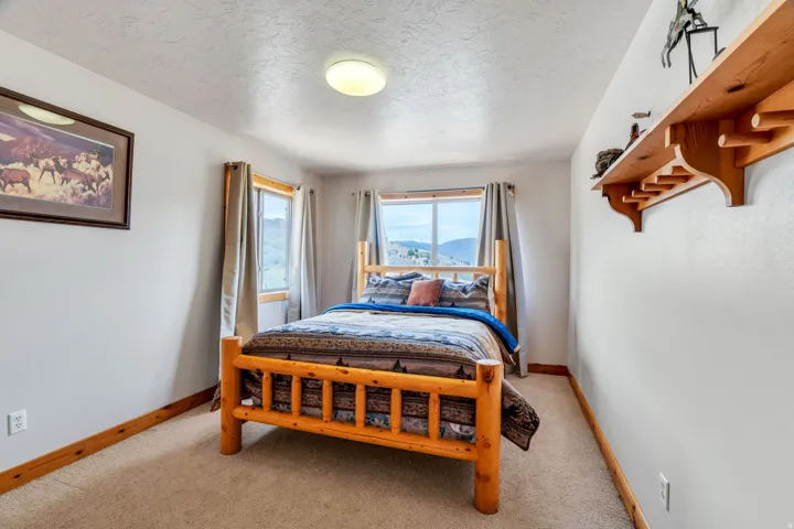 Bedroom featuring a textured ceiling, light colored carpet, and a mountain view