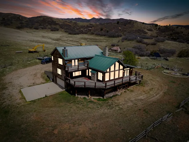 Back of property at dusk featuring driveway, a garage, a deck with mountain view, and a chimney