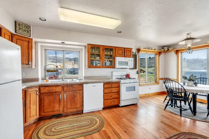 Kitchen featuring wood finish cabinets, white appliances, light wood-type flooring, a textured ceiling, and decorative light fixtures