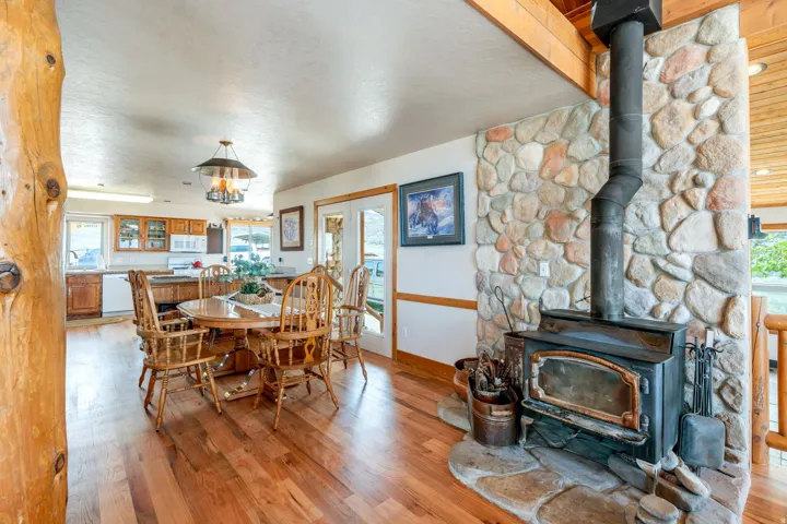 Dining room with a wood stove, light wood-type flooring, a textured ceiling, hanging lights, and french doors