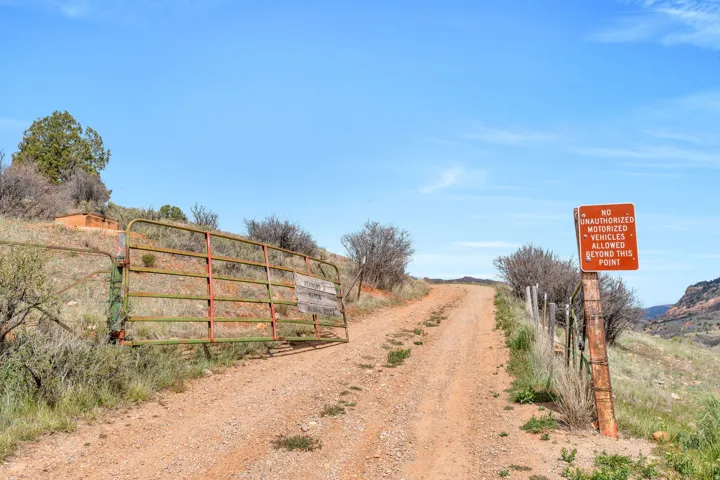 View of dirt / gravel road with a gate and a view of rural / pastoral area