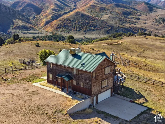 Two-story residence featuring wood-plank siding, a metal roof, a concrete driveway, an attached garage, and mountain scenery