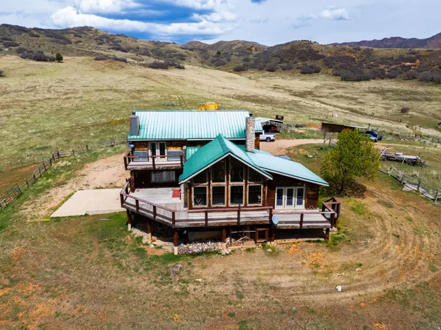 Back of property with a view of rural / pastoral area, a deck with mountain view, a metal roof, and a chimney