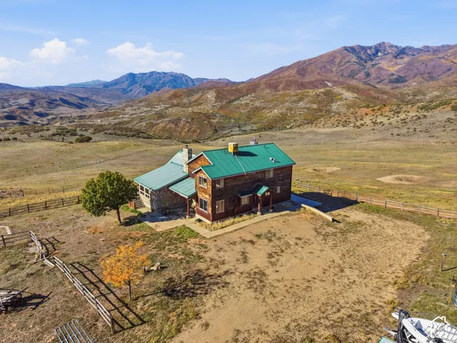 Multi-level rustic residence featuring wood siding, stone exterior masonry, a green metal roof, and an expansive mountain backdrop