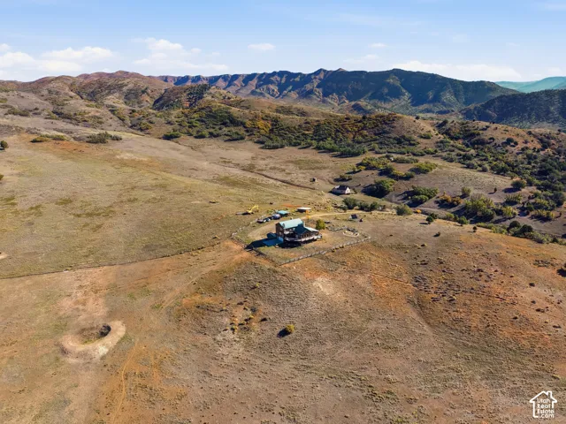 Expansive rural acreage featuring rolling hillside terrain, mature native vegetation, and mountain silhouettes