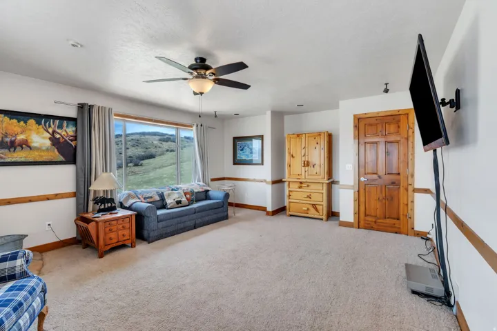 Living area featuring light colored carpet and a ceiling fan