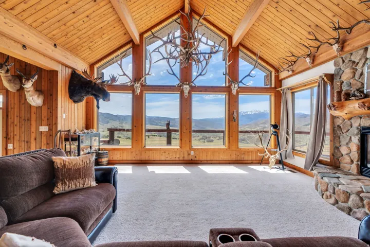 Carpeted living area featuring a high wooden beamed ceiling, a mountain view, a fireplace, and wooden walls