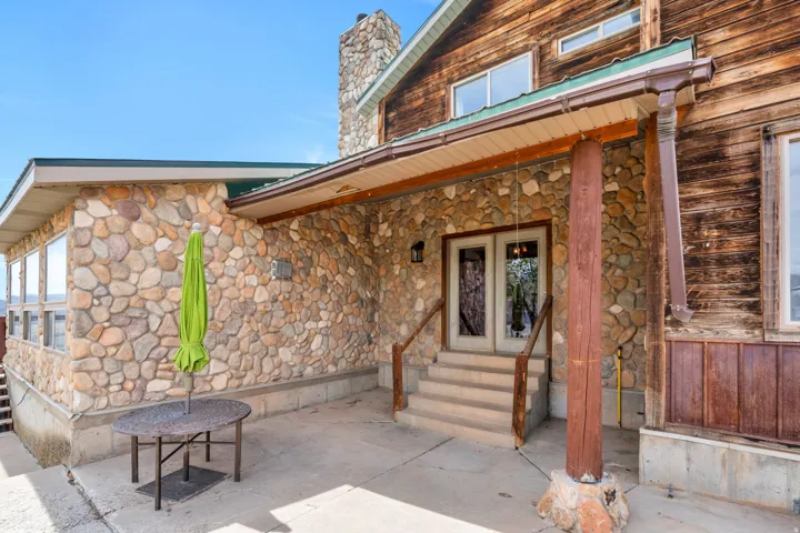 View of exterior entry featuring stone siding and a chimney