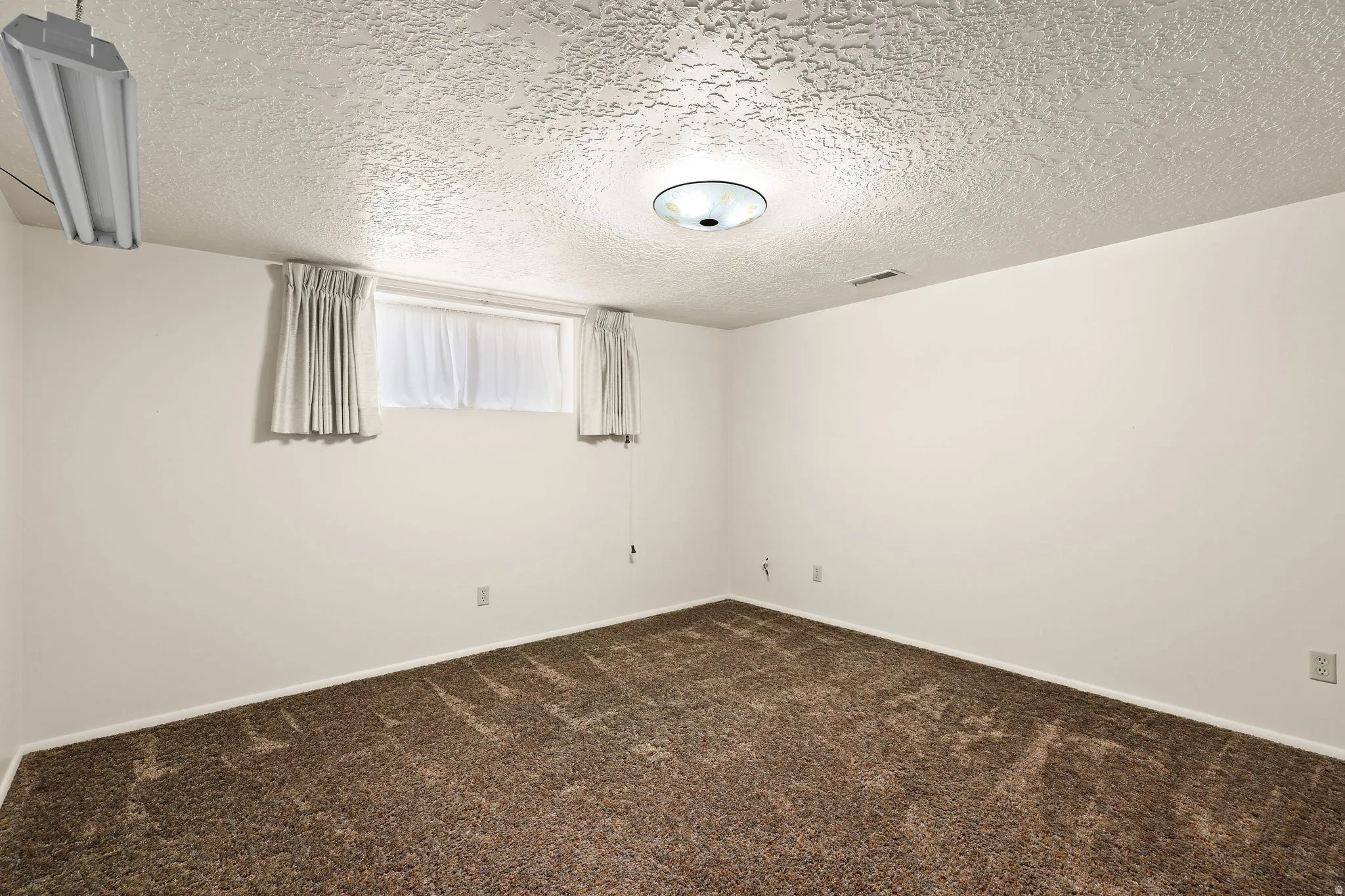 Unfurnished room featuring a textured ceiling and dark colored carpet