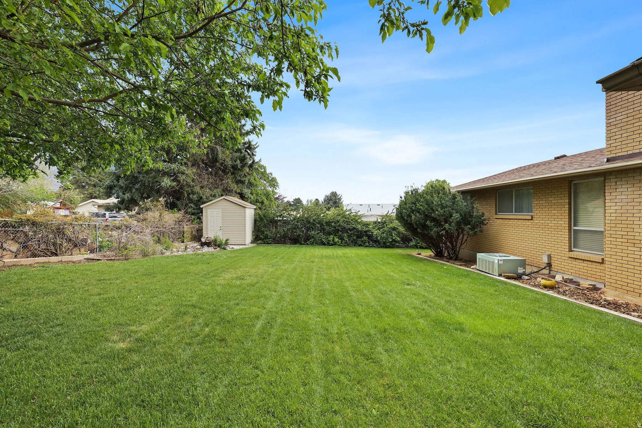 Fenced backyard featuring a storage shed
