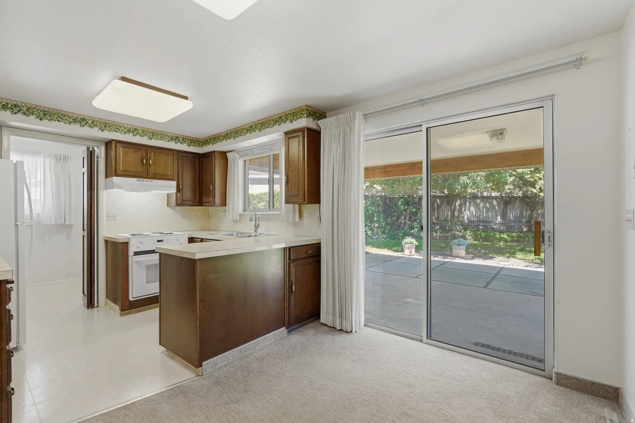 Kitchen featuring wood cabinetry, white appliances, and a breakfast bar