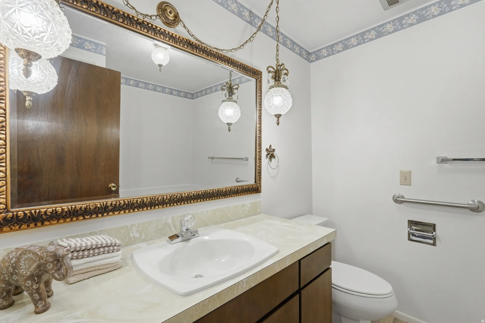 Bathroom featuring a vanity with an integrated sink, a large ornate framed mirror, and a toilet