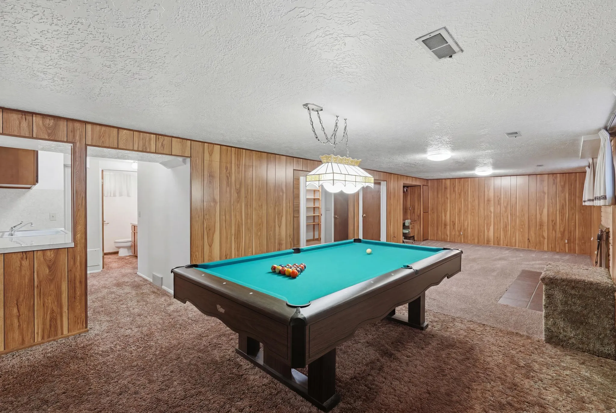 Recreation room featuring wood-finish wall paneling, recessed lighting, and carpet flooring