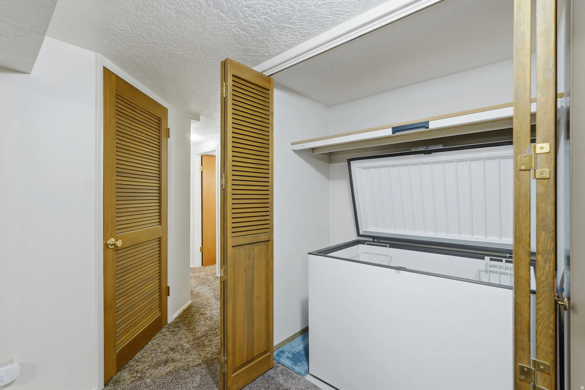 White walls with textured ceiling and wood-finish louvered doors