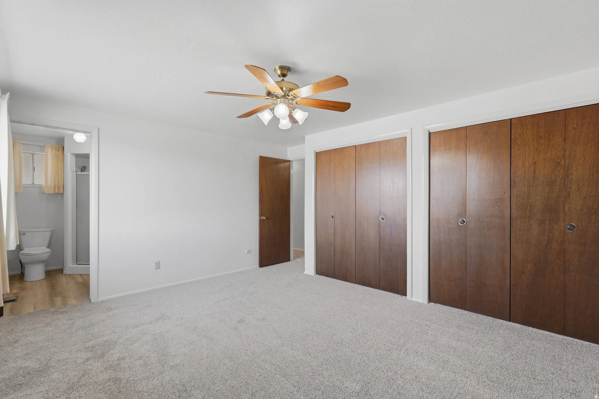 Spacious room featuring light-toned carpeting and a ceiling fan with integrated lighting