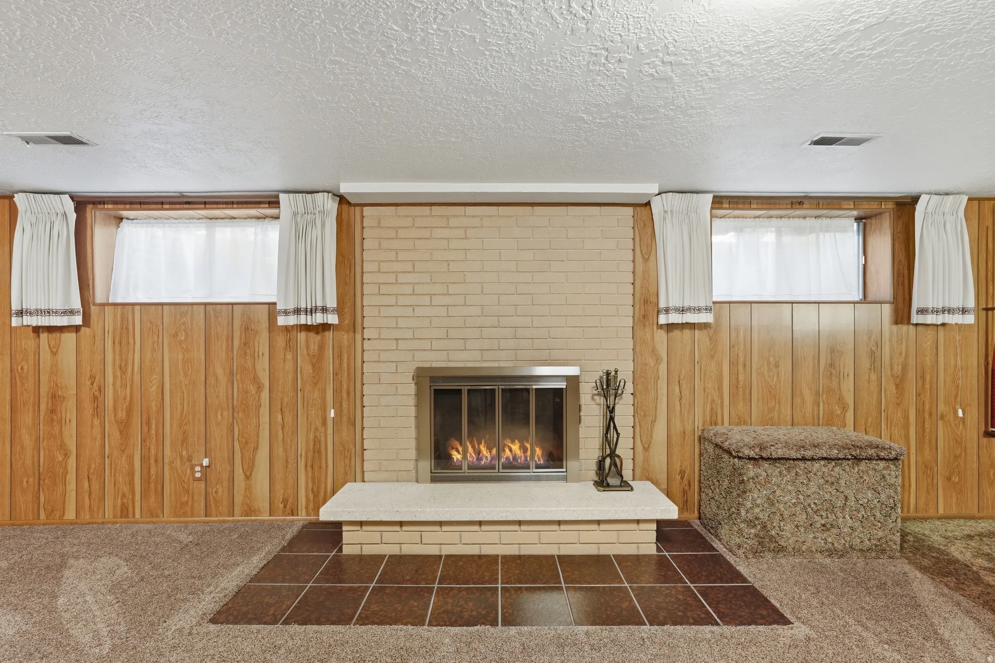 Brick fireplace with a raised hearth, stainless steel insert, and tile surround