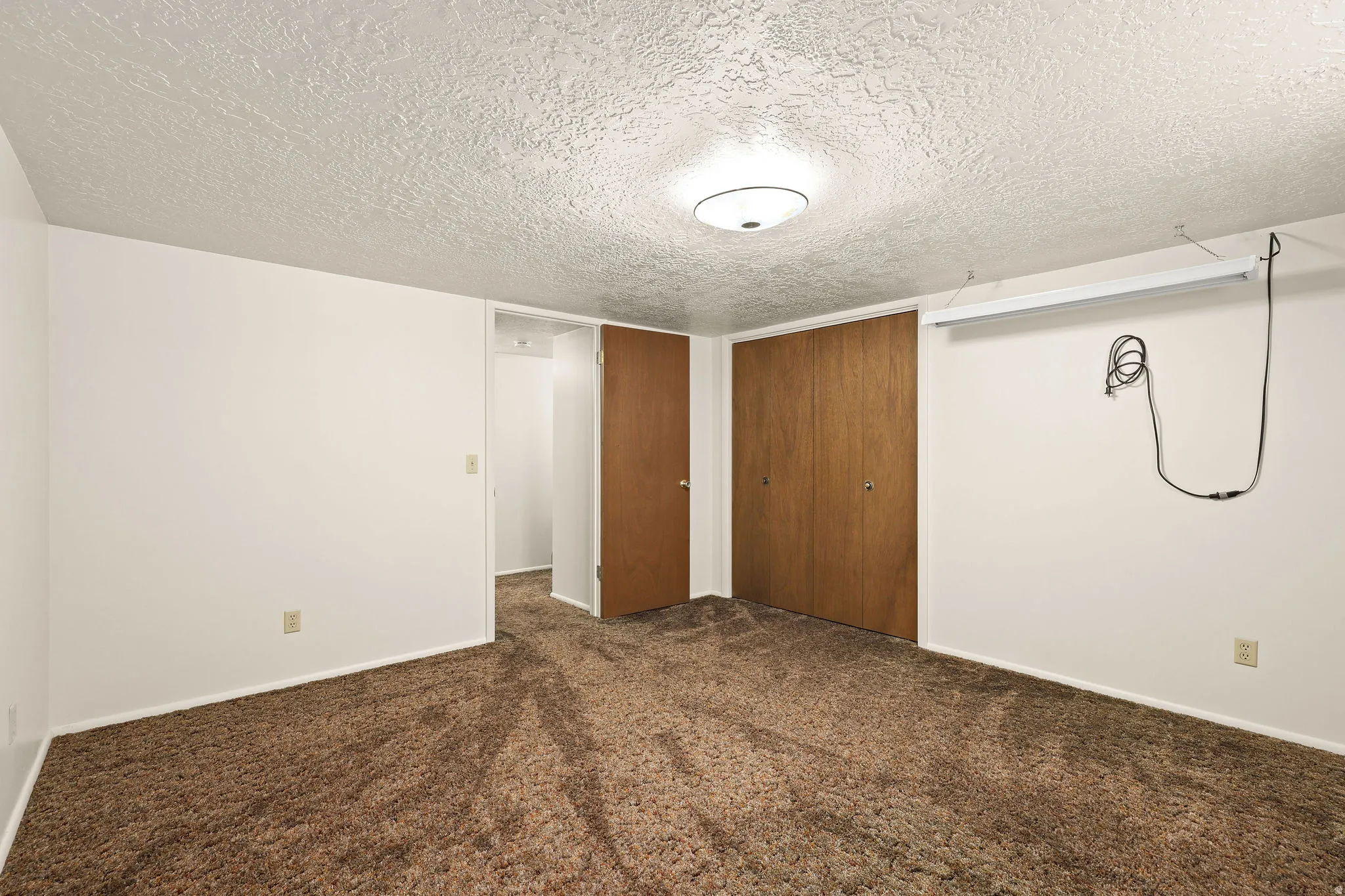 Unfurnished bedroom with a textured ceiling, dark colored carpet, and a closet