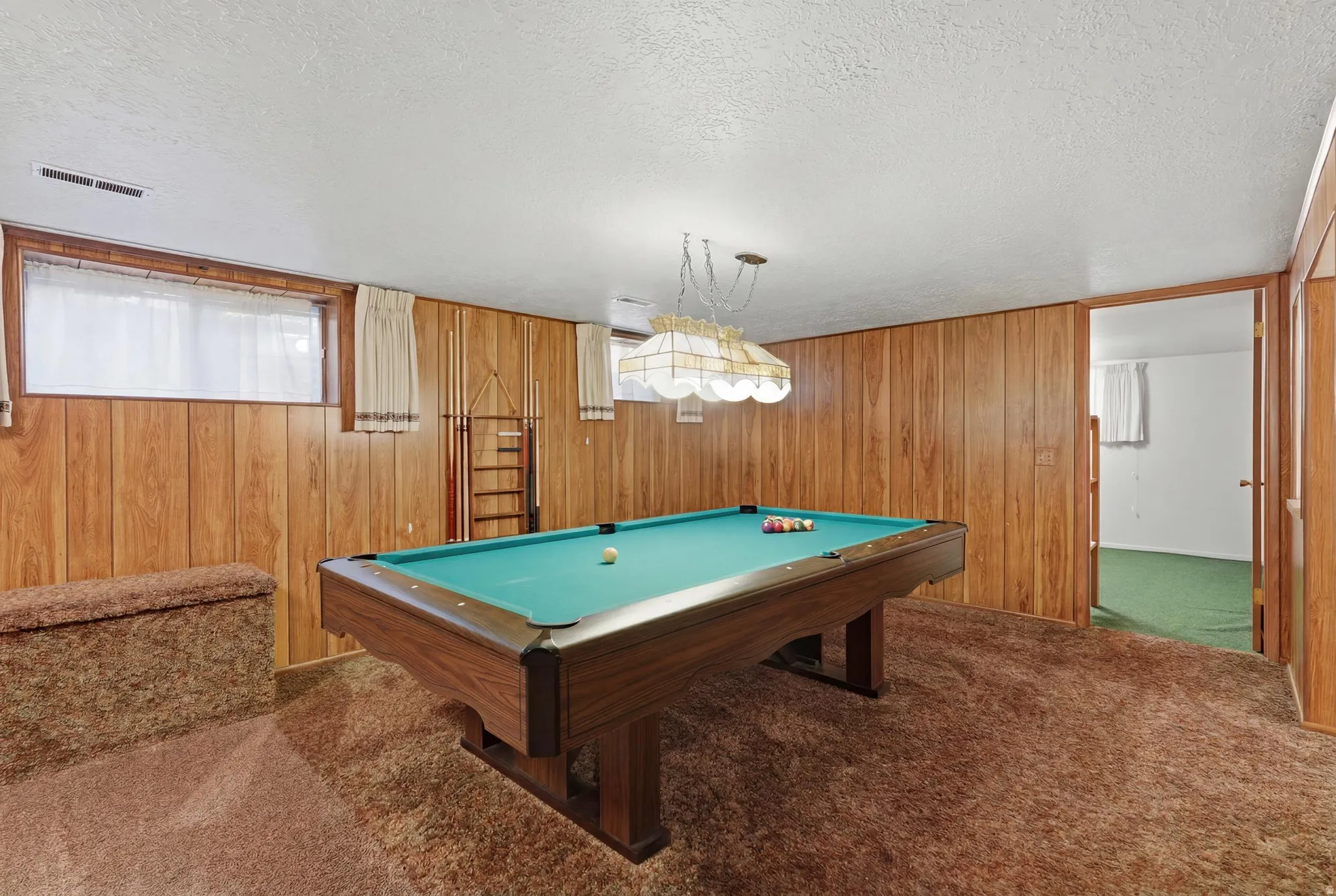 Recreation room featuring wood paneling, an overhead chandelier, and a large window