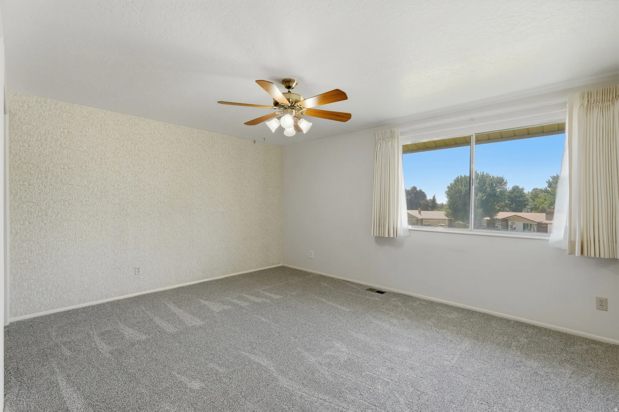 Spacious room featuring light gray carpet flooring and a ceiling fan with integrated lighting