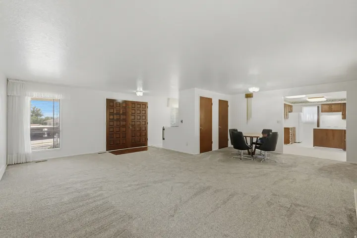 Spacious living area featuring light-toned carpeting and white walls