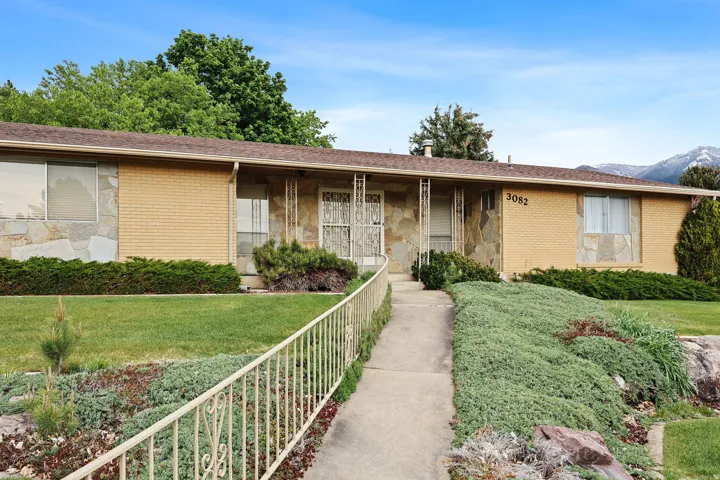 Ranch-style house featuring brick and stone, a front lawn, covered porch, a shingled roof.
